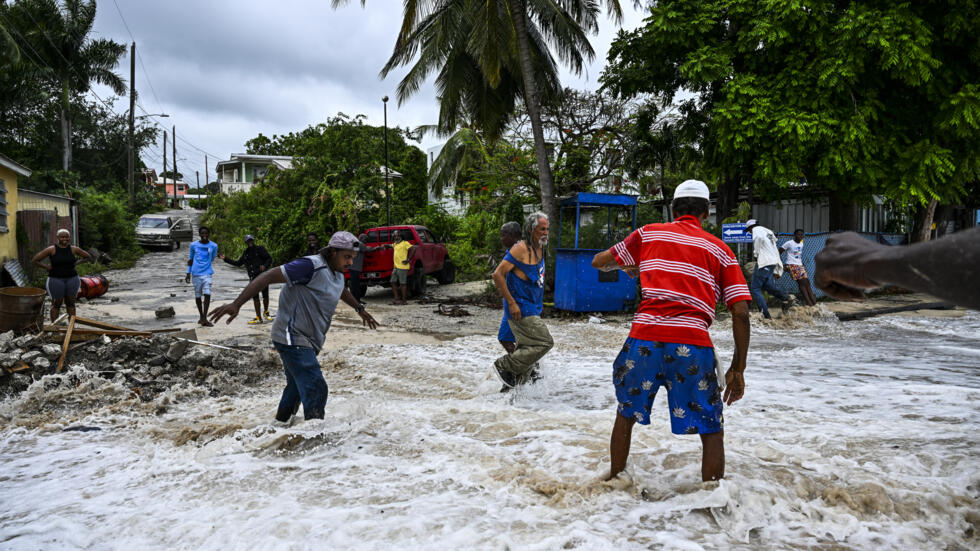 People walk through flooding from seawater after hurricane Beryl passes in the parish of Saint James, near Bridgetown, Barbados, July 1, 2024. Photo: Chandan Khanna, AFP