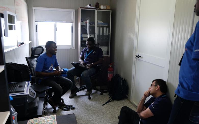 Jalal Shah (lower right), meets with Muhammad Kalli (left) and Ekue Ayih (centre) at the IOM hub in Dikwa. Photo: WFP / Erika Iglesias